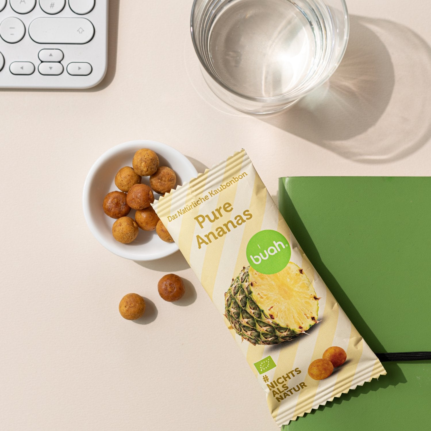 runde, gelbliche Ananas Kaubonbons in einer Schale neben einer Packung Kaubonbons auf einem Notizbuch