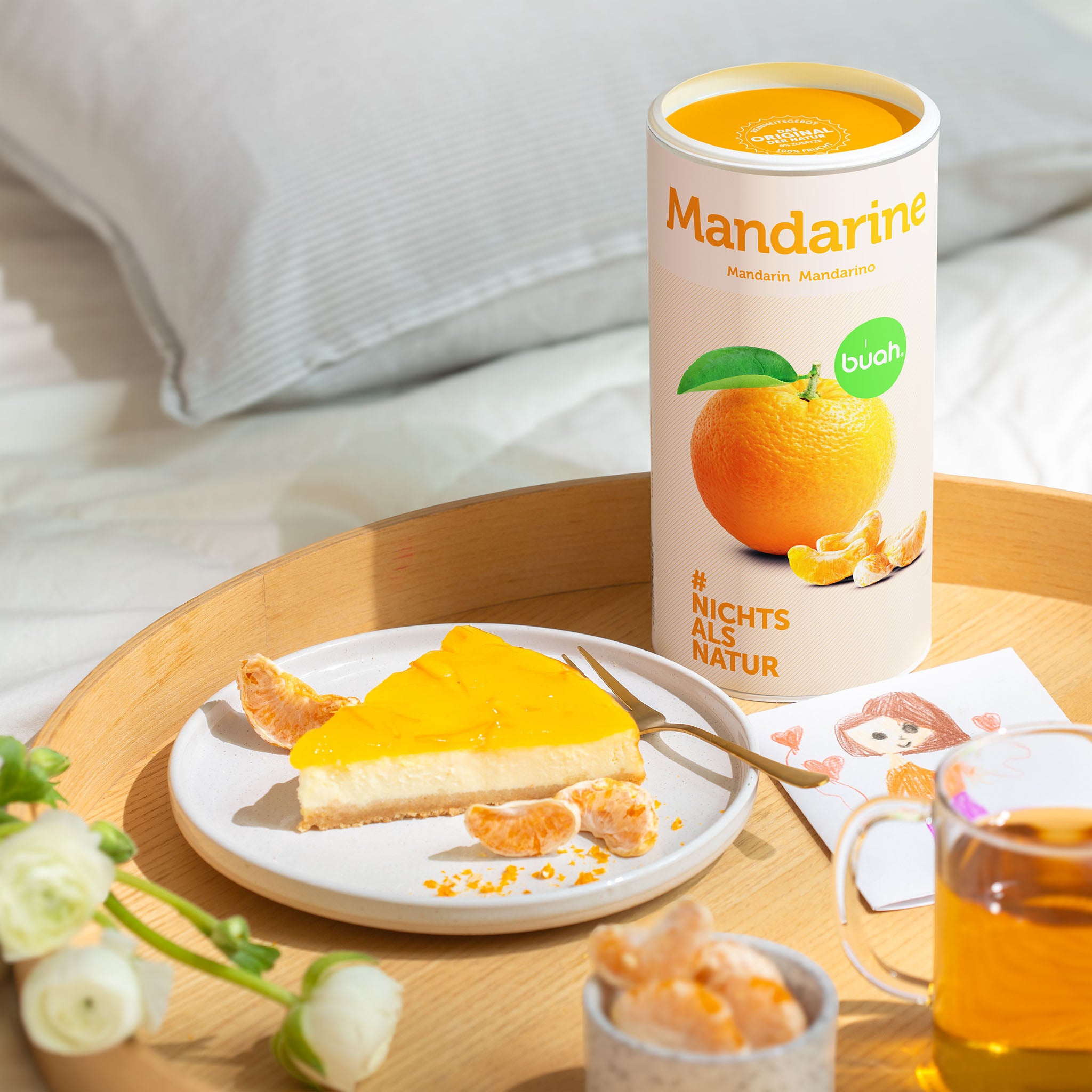 Dose buah Mandarine auf rundem Beistelltisch neben einem Teller mit Mandarinenkuchen