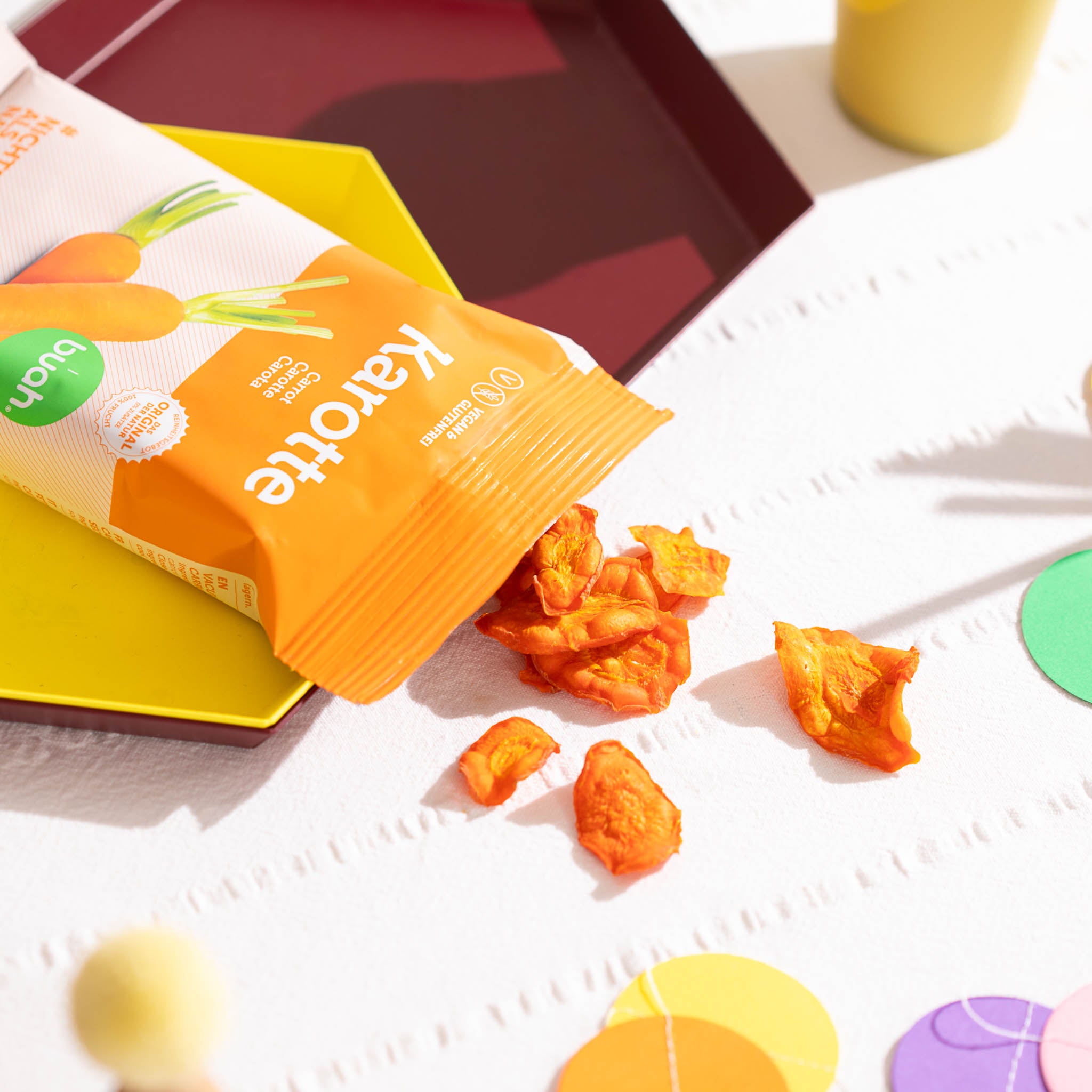 Vakuumgetrocknete buah Karottenchips fallen aus einer Packung Karottenchips auf eine Picknickdecke