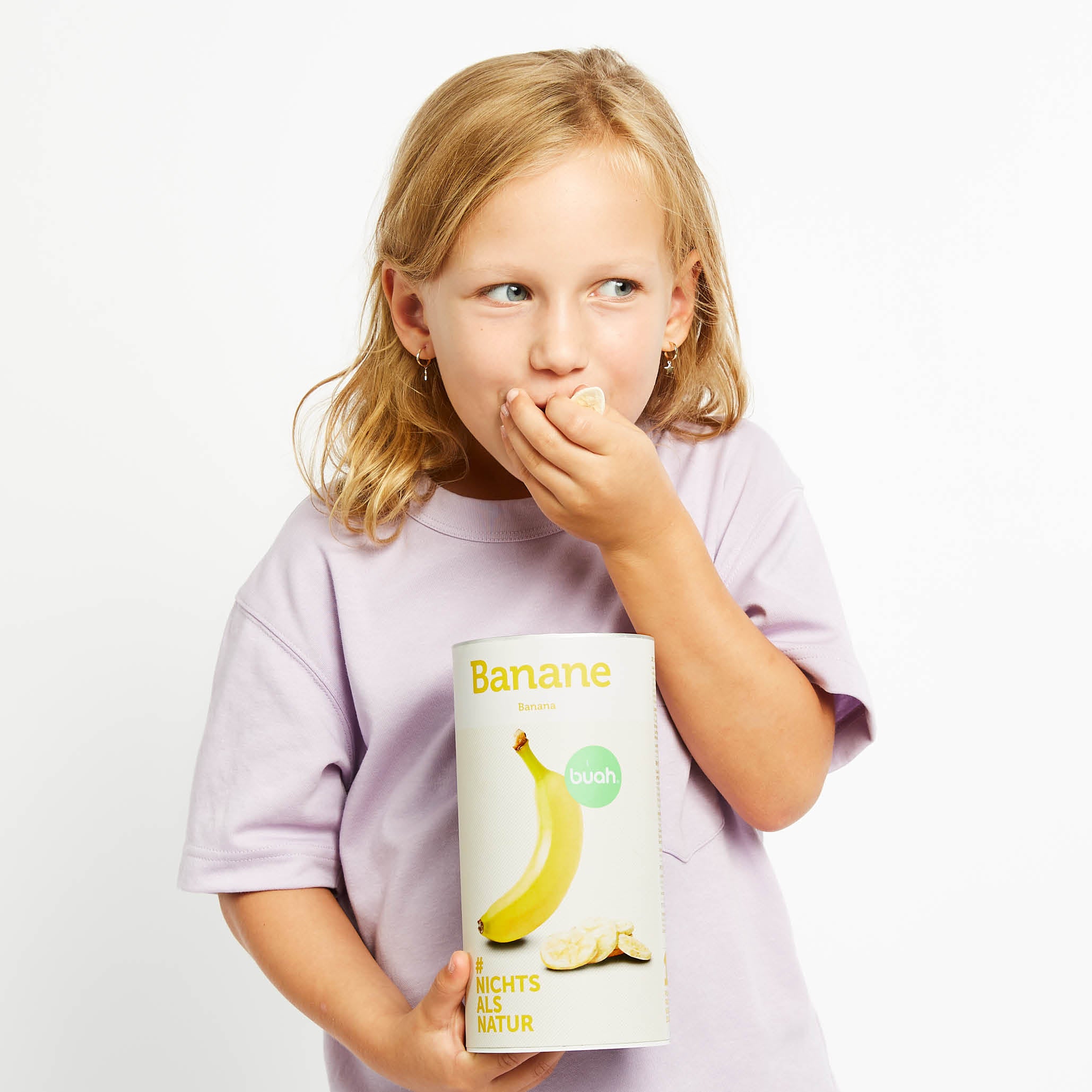 Junges Schulkind hat Dose buah Bananen in der Hand und isst diese