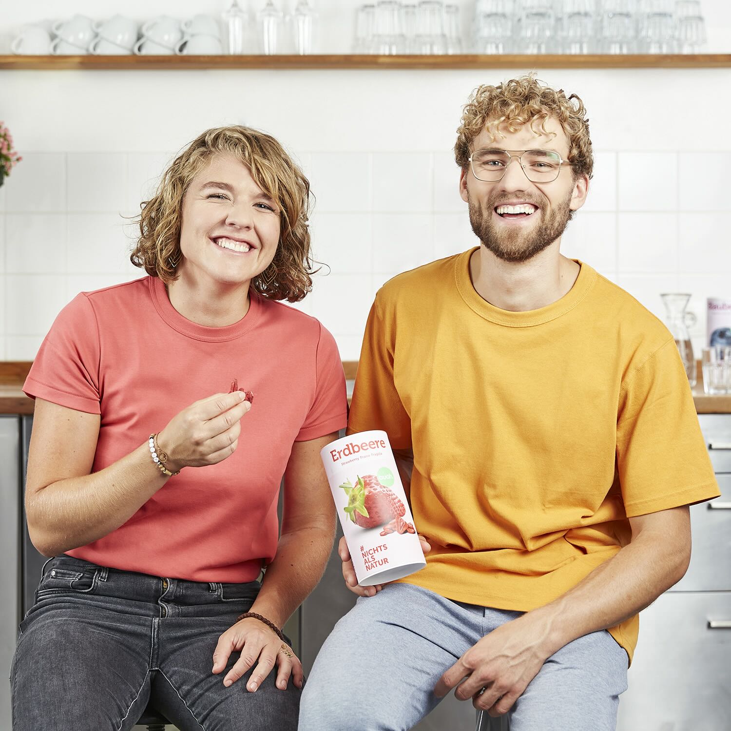 Gruender von buah Jessica und Daniel lachen in die Kamera und halten eine Dose buah Erdbeeren