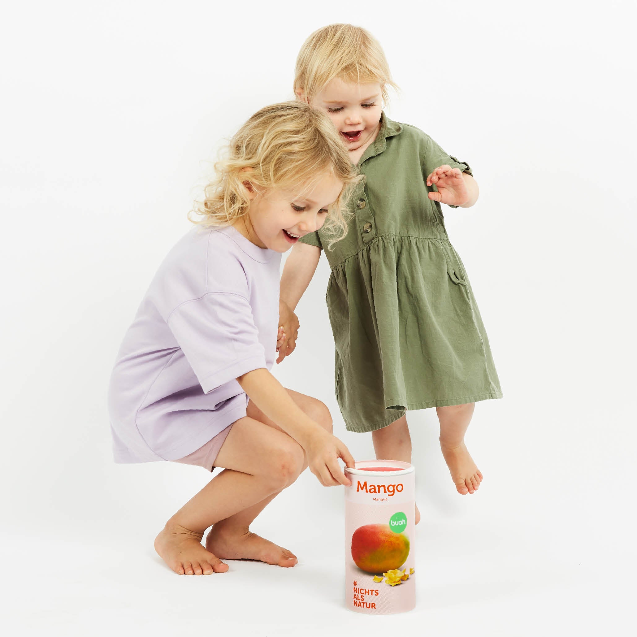 Zwei kleine Kinder lachen und greifen nach einer Dose buah gefriergetrocknete Mango