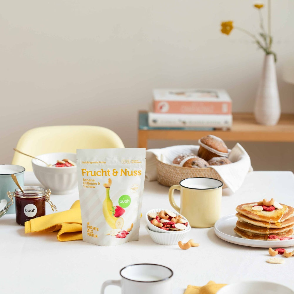 buah Frucht & Nuss Mischung steht auf einem FrĂĽhstĂĽckstisch neben einer Schale mit der Frucht & Nuss Mischung