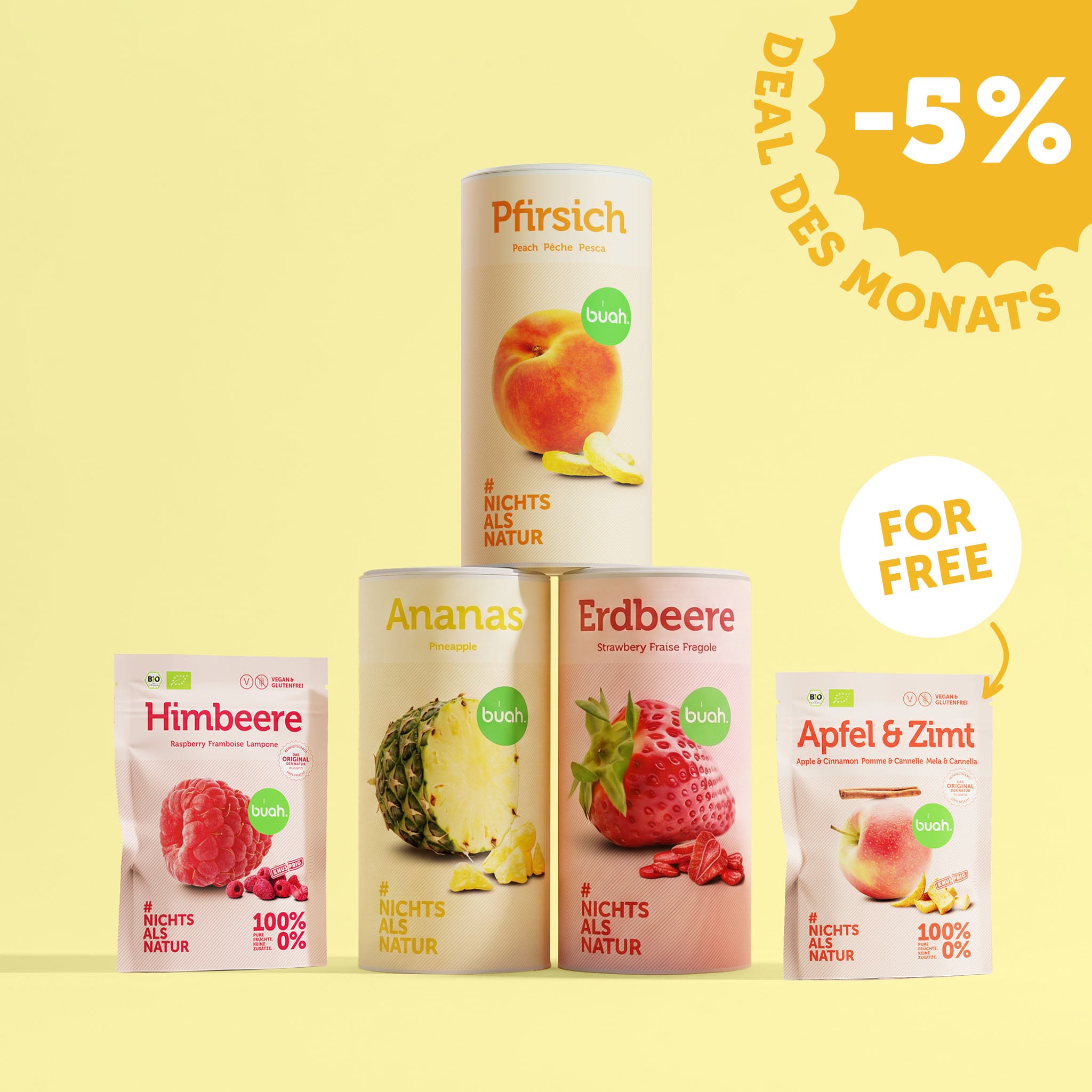 Eine große Dose buah gefriergetrocknete Pfirsiche steht auf zwei weiteren Dosen Ananas und Erdbeere. Links davor steht ein kleiner Beutel Himbeere, rechts ein kleiner Beutel Apfel & Zimt mit einem „FOR FREE“-Hinweis. Oben rechts ist ein „Deal des Monats -5%“-Badge.