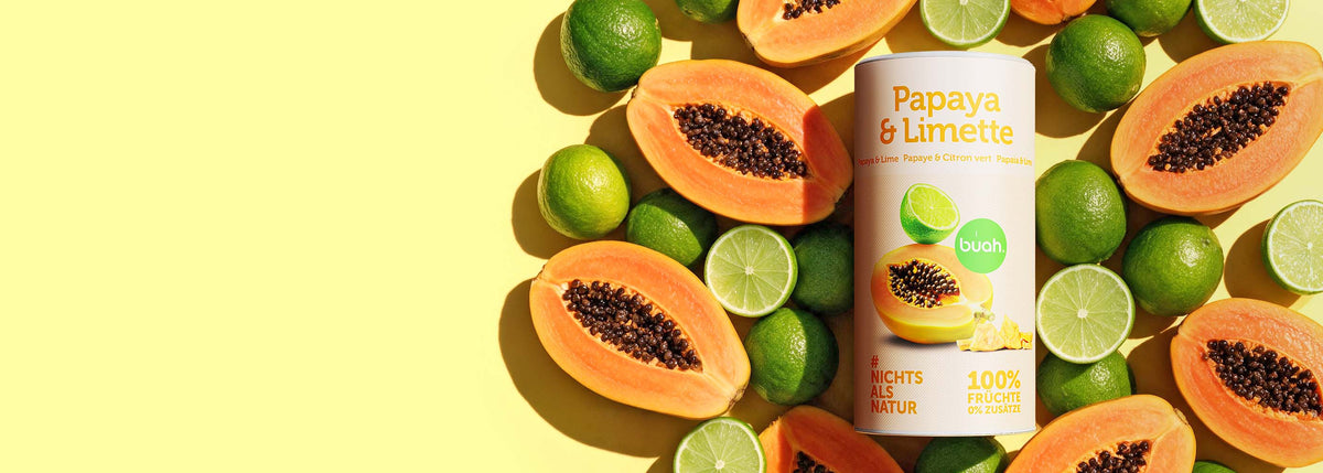 buah-Dose „Papaya & Limette“ mit gefriergetrockneter Papaya und Limette, umgeben von Papayahälften und Limetten auf gelbem Hintergrund; „Nichts als Natur“, „100 % Früchte, 0 % Zusätze“.