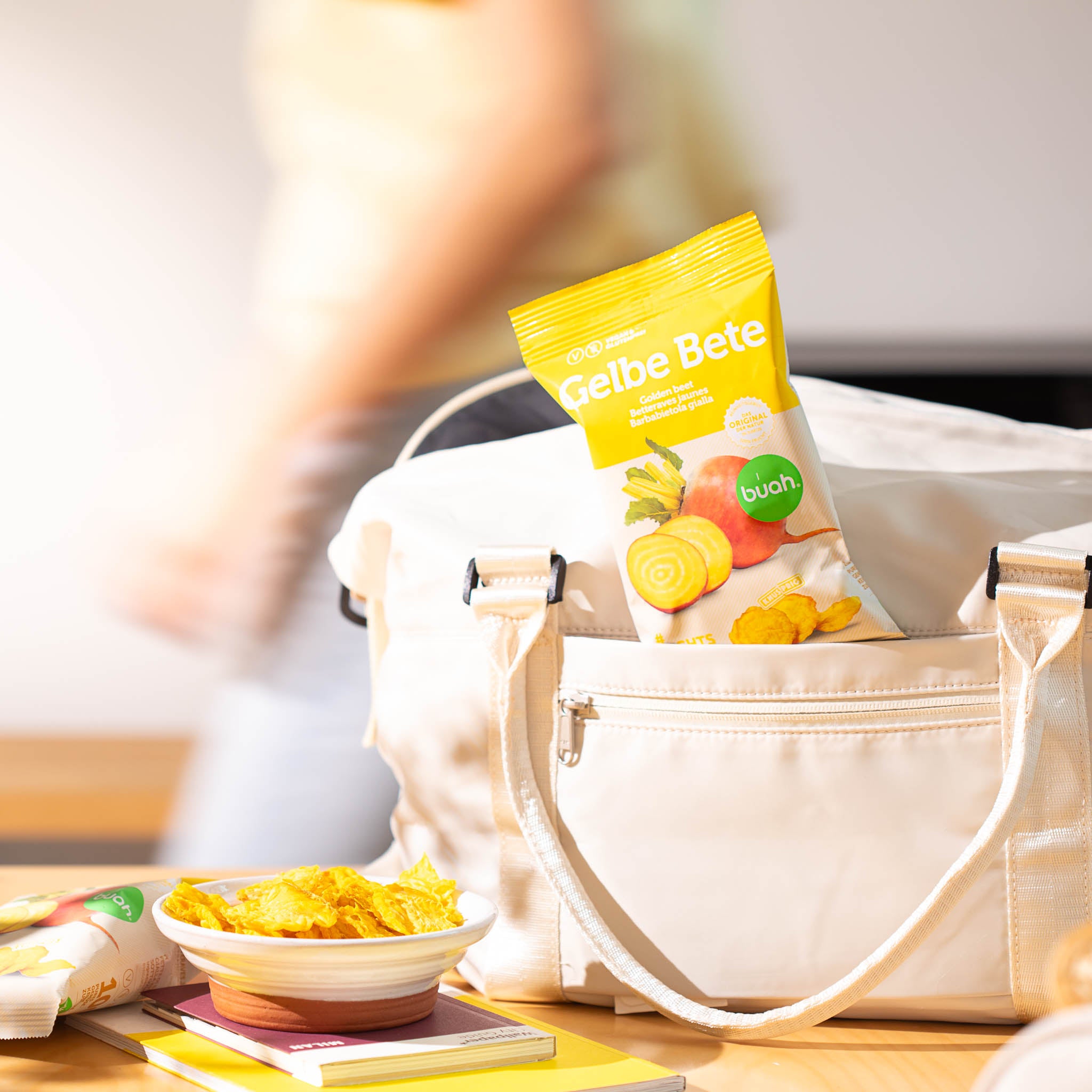 buah Gelbe Bete Gemuesechips stecken im Fach einer Tasche mit buah Gemuesechips in einer Schale im Vordergrund