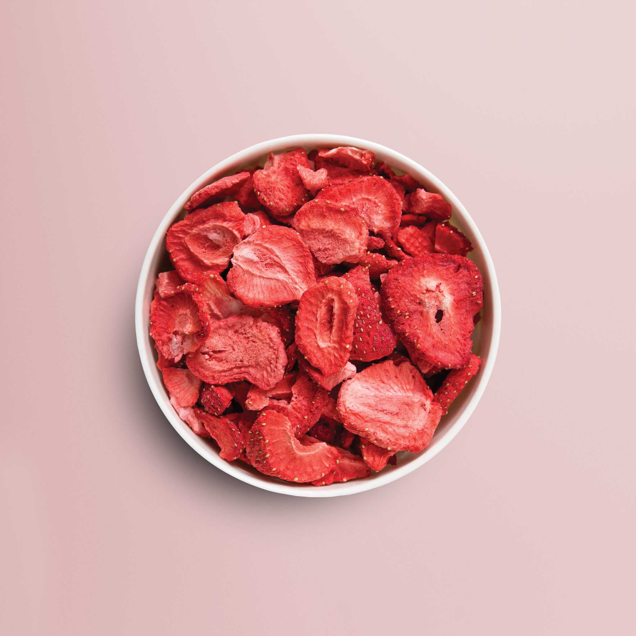 buah gefriergetrocknete Erdbeeren in einer Schale vor rosa Hintergrund