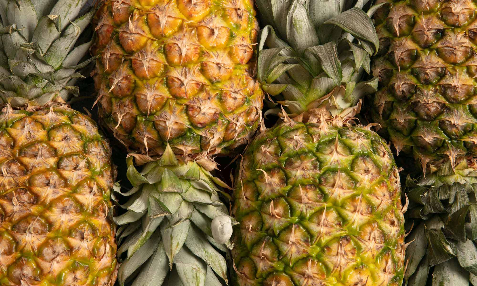 Viele frische Ananas Fruechte neben und aufeinander 