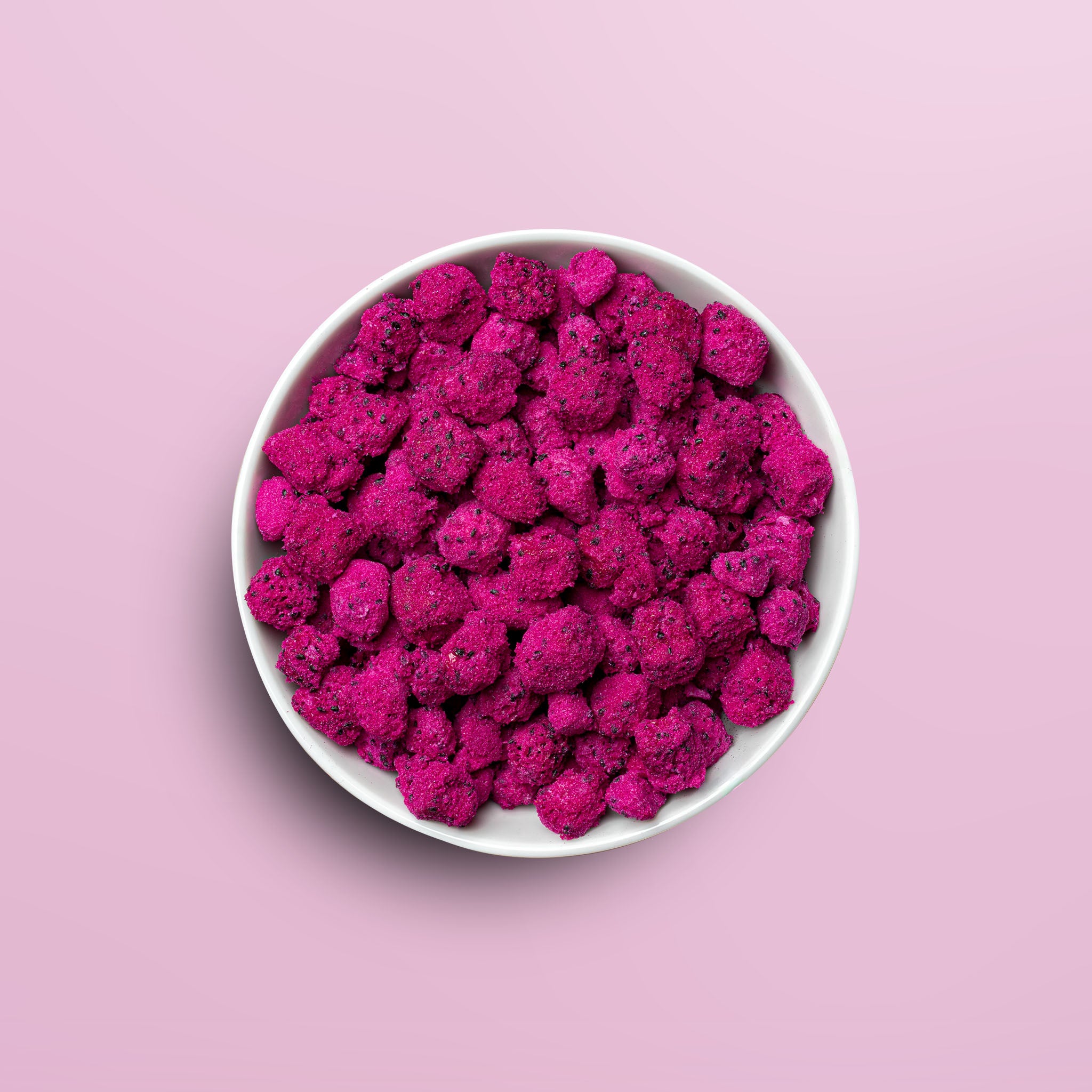 Weisse Schale mit buah gefriergetrockneter Drachenfrucht in sattem pink vor rosa Hintergrund