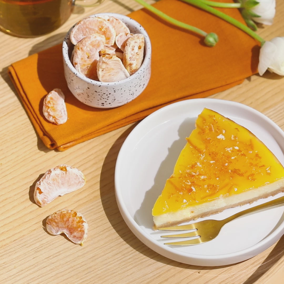 buah Mandarine in Schüssel neben einem Mandarinenkuchen auf einem Teller